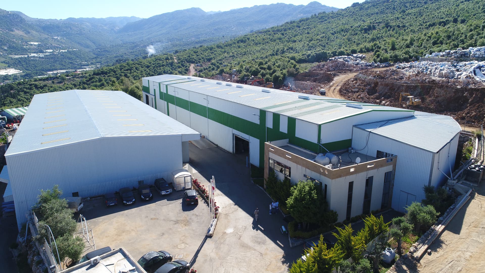 Aerial view of DC7 group factory buildings in a green mountainous landscape